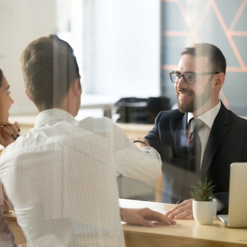 Man shaking hands with couple across a counter