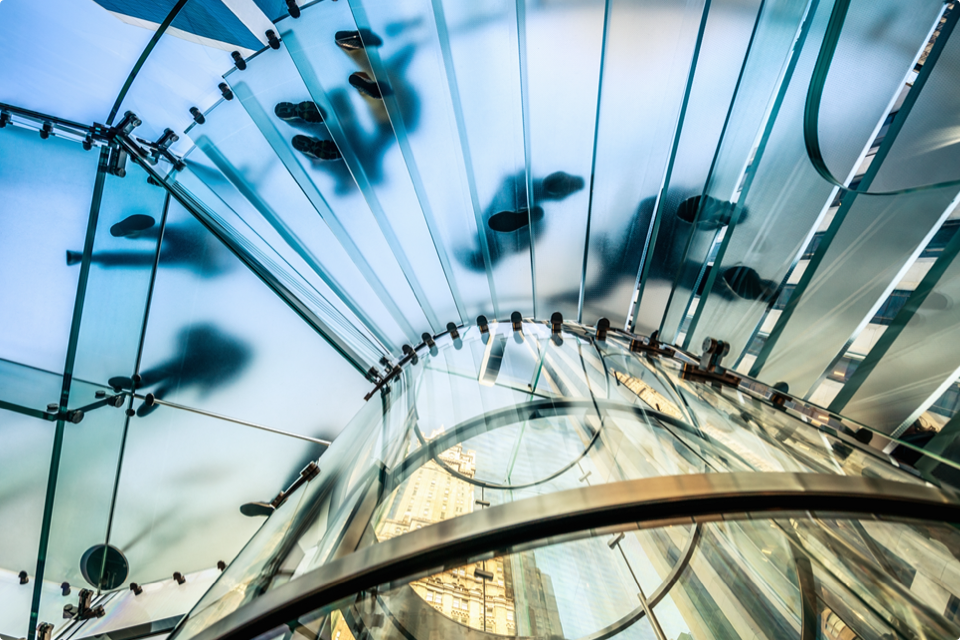 Looking at glass staircase from below with people walking on it