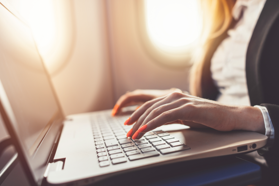 Woman typing on a laptop with orange nails